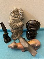 Lot of five indigenous sculptures on a blue surface against a beige wall. Front close-up view.