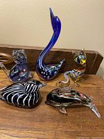 Full view of all five Murano glass animal sculptures on a wooden surface.