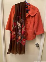 Tangerine jacket with brown floral scarf hanging on a door, showing front and collar details.
