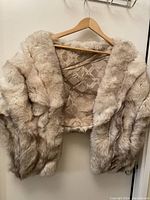 Front and interior view of the light-colored real fur shawl, showing the dense fur texture and diamond-pattern satin lining.