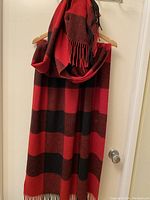 Full view of the red and dark brown checkered scarf hanging, showing size and pattern.