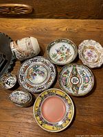 Overview of all ceramic items arranged on wooden surface including plates, mug, and trinket boxes