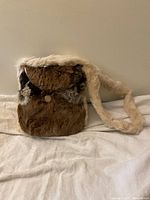 Front view of vintage fur shoulder bag with flap closed and visible bakelite button, bag laid flat on surface.