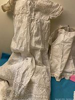 Photo showing white vintage linen baby gown with extensive floral embroidery and lace trim at bottom