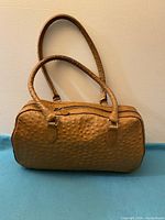 Front view of brown textured leather handbag with double handles and single zipper