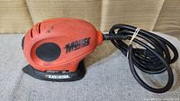 Side view of the orange and black Black & Decker Mouse sander/polisher showing the brand and model name clearly with attached power cord.