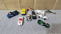 Wide view of the 10 toy vehicles showing all items including cars, motorcycle, helicopter, and rover.