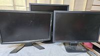 Three 19-inch monitors: two rectangular Acer monitors in front, one square monitor behind them, all with black frames and stands.