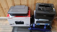 Five printers stacked, includes a Canon PIXMA printer box and two visible laser printers.
