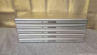 Five Apple MacBook Pro laptops stacked horizontally showing thickness and side ports.