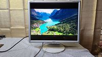 NEC MultiSync 90GX2 19 inch LCD monitor powered on displaying landscape image. Monitor has silver bezel and round white base stand.
