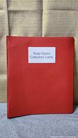 Closed red binder labeled 'Soap Opera Collectors Cards' on front cover.