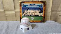 Overall view of signed baseball in plastic case placed in front of a 10 x 12 plaque featuring the 1993 Toronto Blue Jays World Champions team photo.