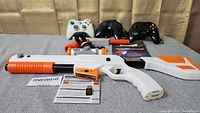 Nintendo Zapper light gun along with manuals and warranty card, three wired controllers in the background.