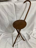Full view of the vintage wooden cane and stool combination, showing the curved hook handle and round seat with tripod legs extended.