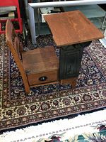 Side angled view of antique wooden children's desk showing oak wood construction and metal base with side storage drawer and cupboard below.