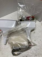 White plastic Pampered Chef Boil Control and a bag of assorted metal piping tips and small kitchen utensils.