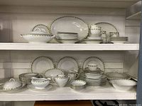 Full set of Austrian china displayed on shelving, showing plates, bowls, cups, saucers and serving platters with ivy leaf pattern and gold/green trim.