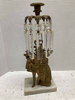 Full view of brass candlestick with couple figurine and hanging rectangular and square crystal prisms