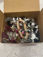 Box of assorted costume jewelry including necklaces and bracelets in various colors and materials such as beads, plastic, and metal.