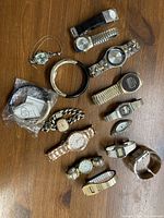 Overview of the collection of 14 watches on wooden surface showing various band styles and colors.