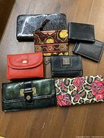 Full lot of 8 wallets and pouch arranged on wood surface showing variety, colors, and styles