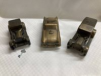 Three brass old car coin banks with one original key placed in front