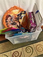 Plastic container holding the circular Star Wars pinata and assorted party supplies including boxed items.