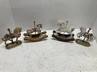 Four horse figurines on white surface showing different styles and colors including rocking horses and carousel horses