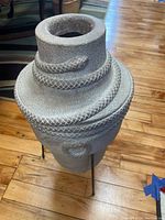 Full view of the faux stone vase showing the snake wrapping around the body and the black stand supporting the vase.