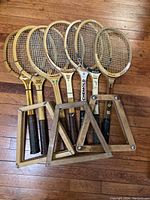Seven wooden tennis racquets with various brand labels including Chemold, shown with wooden handles and stringed heads, together with three wooden ball cages.