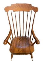 Front view of wooden rocking chair showing the curved top rail, vertical spindles, contoured seat, and armrests.
