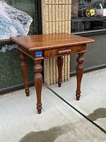Full view of antique small oak table with turned legs and drawer seen from the front corner.