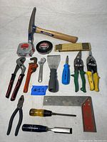 Full lot of hand tools arranged on a white cloth surface showing all items in the lot
