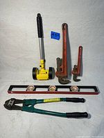 Full view of lot including two pipe wrenches, bolt cutter, spirit level, and mini air hammer.