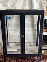 Front view of the large floor standing display cabinet showing double glass doors with lock and glass shelves inside.