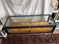 Image showing the full display case cabinet from the top and front angle, highlighting glass panels and metal frame with wooden base visible inside.