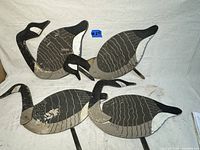 Four handmade wooden Canadian geese decoys arranged with different neck positions, showing overall paint patterns and condition