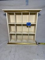 Front view showing all 12 cubby holes and the gold trimmed crown molding and base.