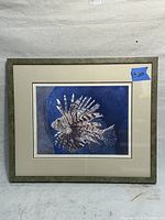 Framed print of a lionfish with blue background in a greenish frame with matting.