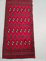 Full view of the vibrant Turkman wool rug showing red background with repeating geometric medallion motifs and detailed borders.