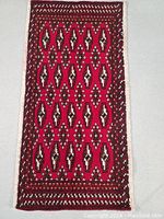 Top full view of Persian Turkman rug showing geometric red and brown pattern with border.