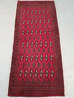 Full top view of the rectangular hand knotted Turkman wool rug with traditional geometric oval and diamond motifs in red and black colors.