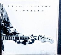 Front cover of the Slowhand vinyl record showing Eric Clapton holding a guitar in black and white.