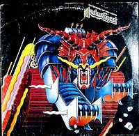 Front view of the Judas Priest 'Defenders of the Faith' vinyl record cover showing the colorful robotic demon artwork with wear marks.