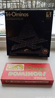 Photo of original boxes for Tri-Ominos and Dragon Dominoes showing branding and packaging condition.