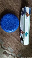 Blue textured balance cushion with small raised bumps on surface next to the Gaiam yoga mat box