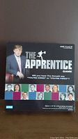 Front view of the box for The Apprentice Game showing Donald Trump and contestants, with title and graphic design from 2004 edition.