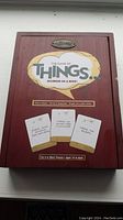 Wooden game box with title 'The Game of Things Humor In A Box' and sample cards on the front of the box.