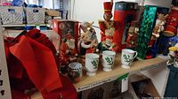 Multiple Christmas nutcrackers, holiday mugs, plush bears, and other figurines arranged on a table.